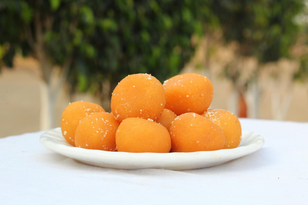 pexels photo 14774070 14774070 A plate of delicious orange laddu sweets outdoors, exuding traditional South Asian flavors.